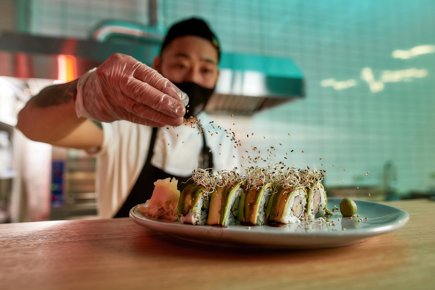 仕上げにセサミとスプラウトを丁寧に振りかける陽だまり珈琲の料理長・小林蒼。皿の上に集中する眼差し。
